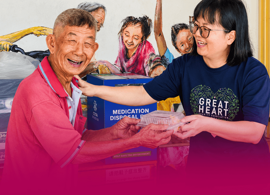 A Great Heart volunteer distributing a lunch box to an elderly man