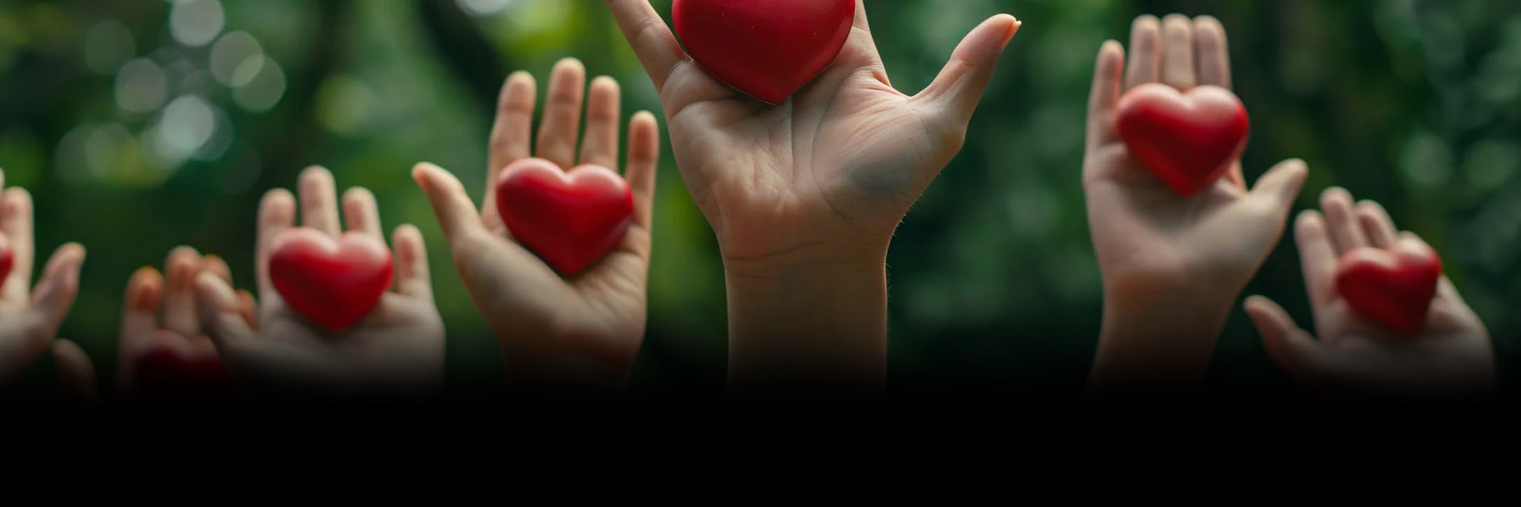 Raised hands holding red hearts in support of volunteering