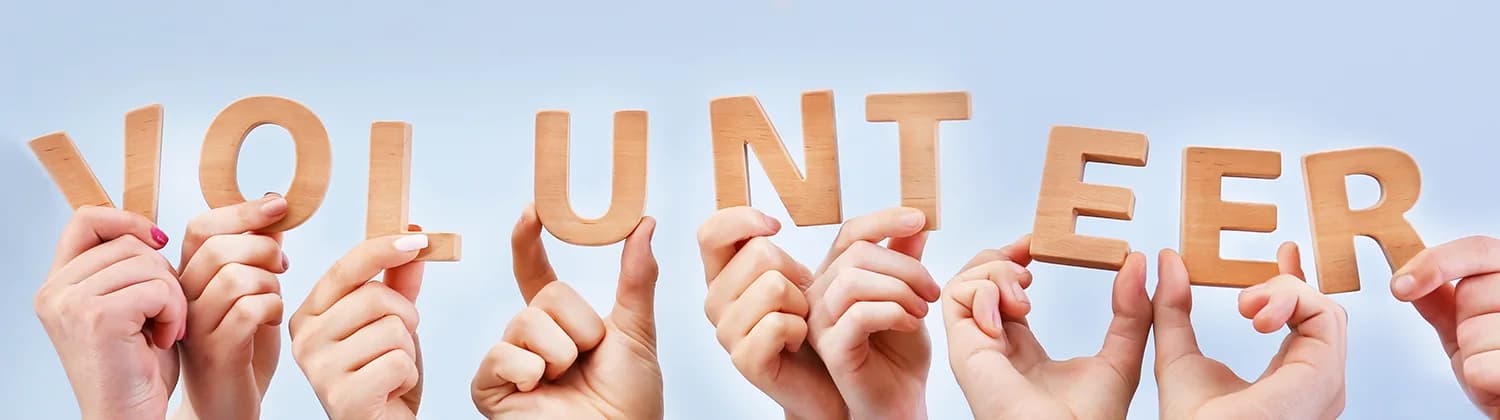 Hands holding wooden letters that spell volunteer