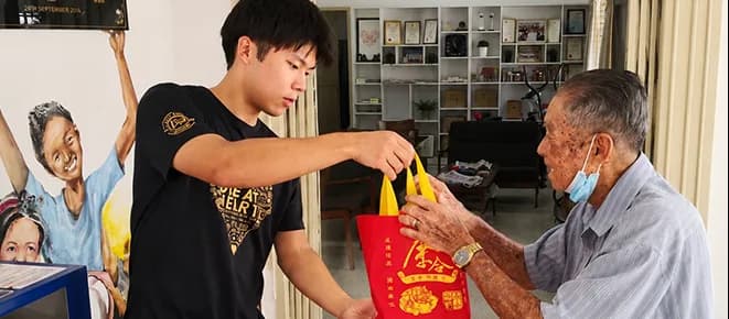 A volunteer presenting a care package to an elderly man