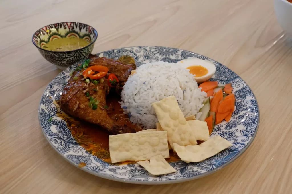 A home-style Malaysian meal of rice, chicken, egg and sides, plated for sharing